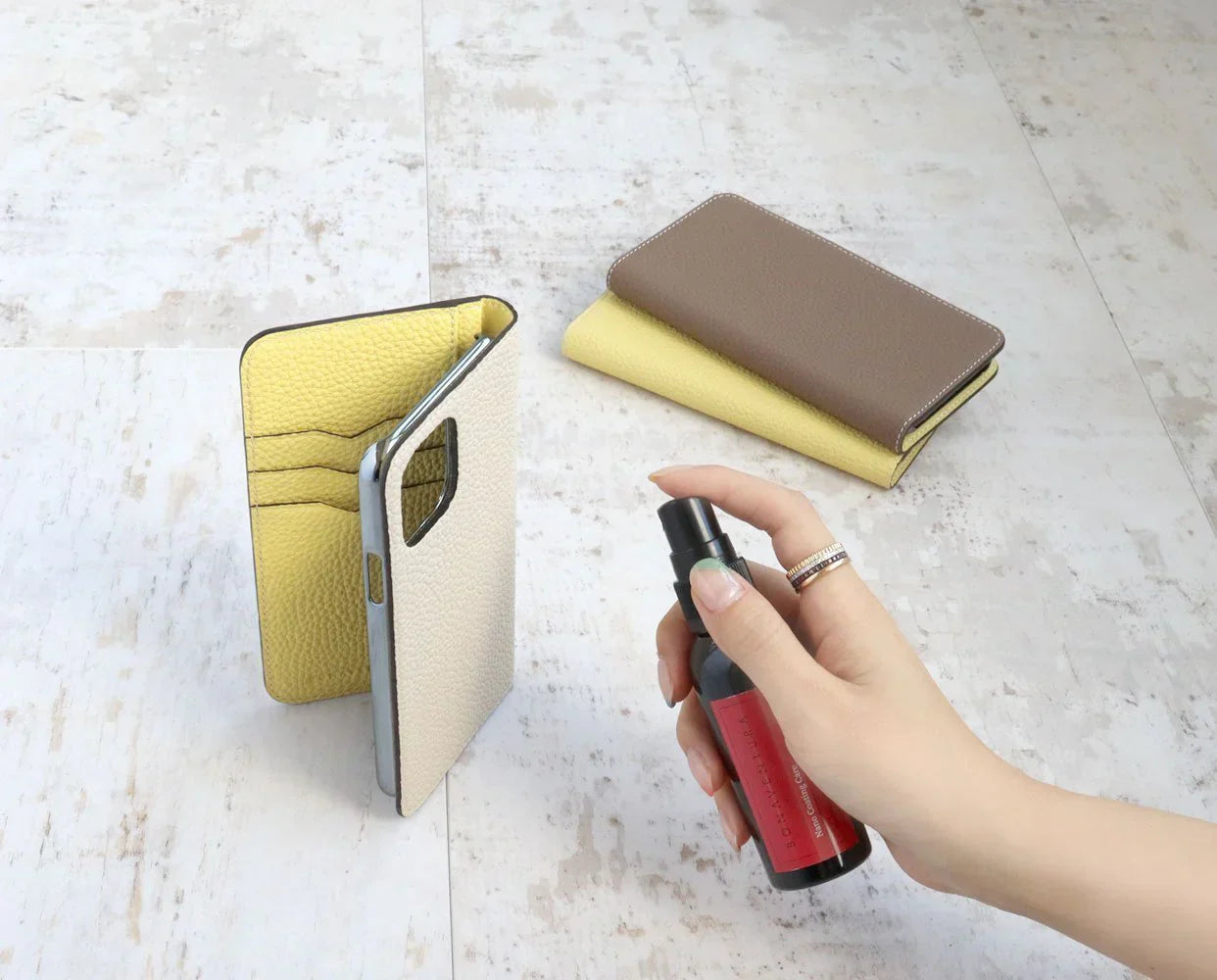 Person removes stains from a fine leather product with a leather care spray.